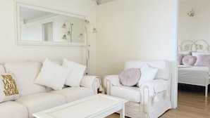 Een witte woonkamer met een bank, fauteuil en salontafel.