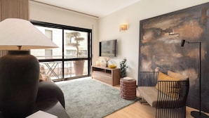 A modern living room with a sofa, a lamp, a TV, and a large abstract painting on the wall.