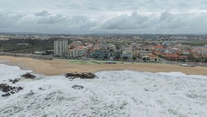 A coastal cityscape with buildings, a beach, and a cloudy sky.