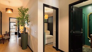 A hallway with a potted plant, a bed, and a bathroom visible through an open door.