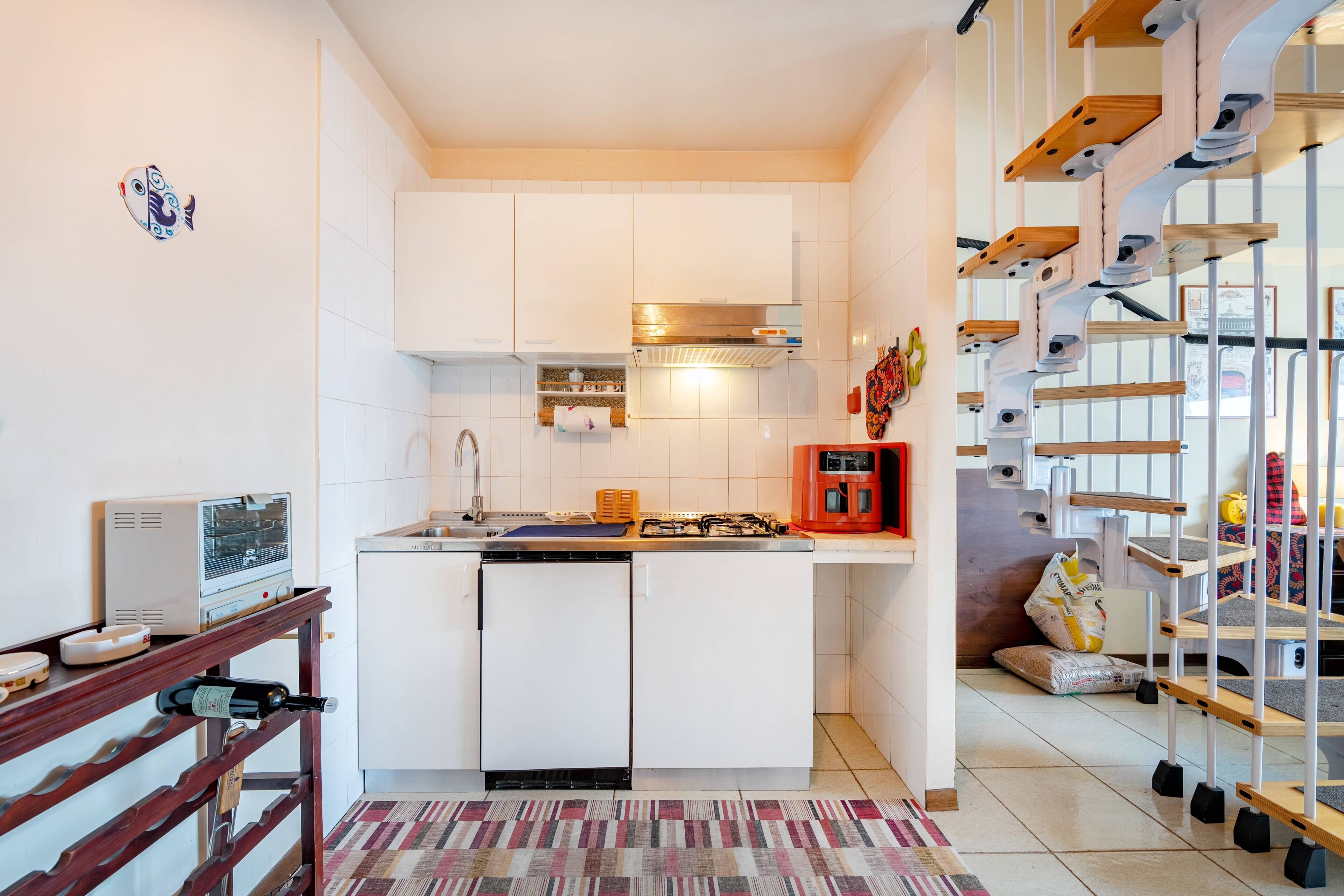 A compact kitchen with white cabinets, a built-in oven, and a small refrigerator.