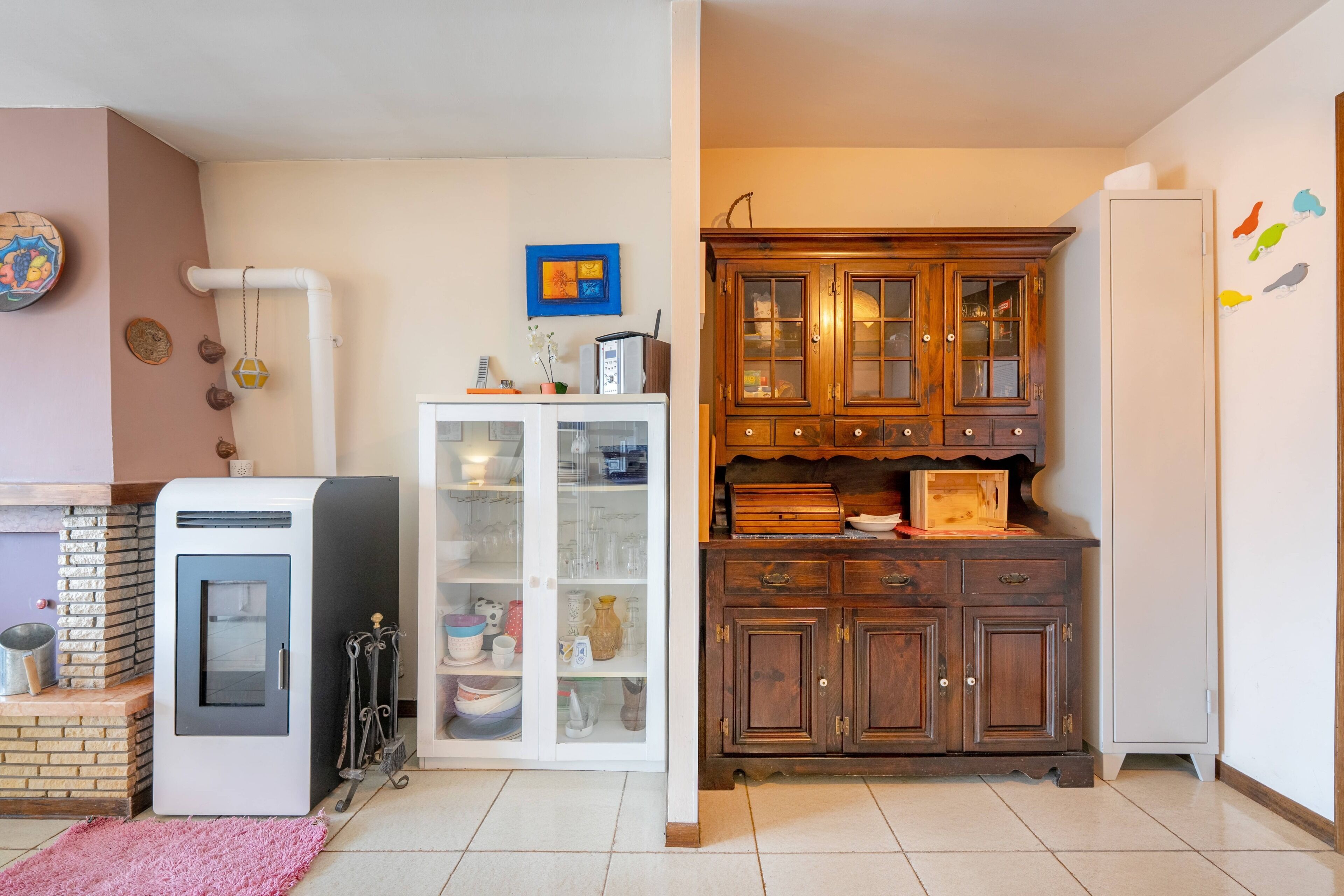 Eine Küche mit einem Kühlschrank, einem Schrank mit Glastüren und einem Holzkasten mit Schubladen.