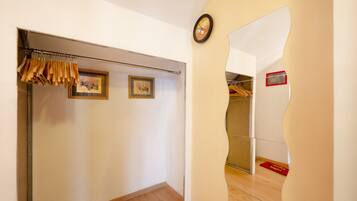A hallway with a coat rack, framed pictures, a clock, and a red mat on the floor.