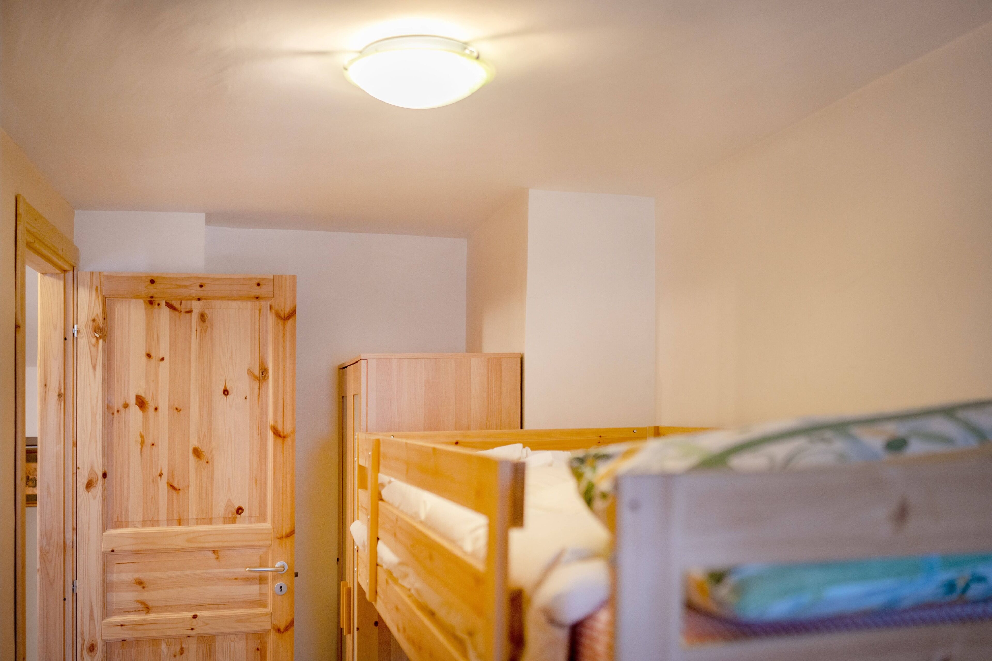 Una camera da letto con un letto a castello in legno, un'armadio in legno e una lampada a sospensione.