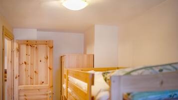 Una camera da letto con un letto a castello in legno, un'armadio in legno e una lampada a sospensione.