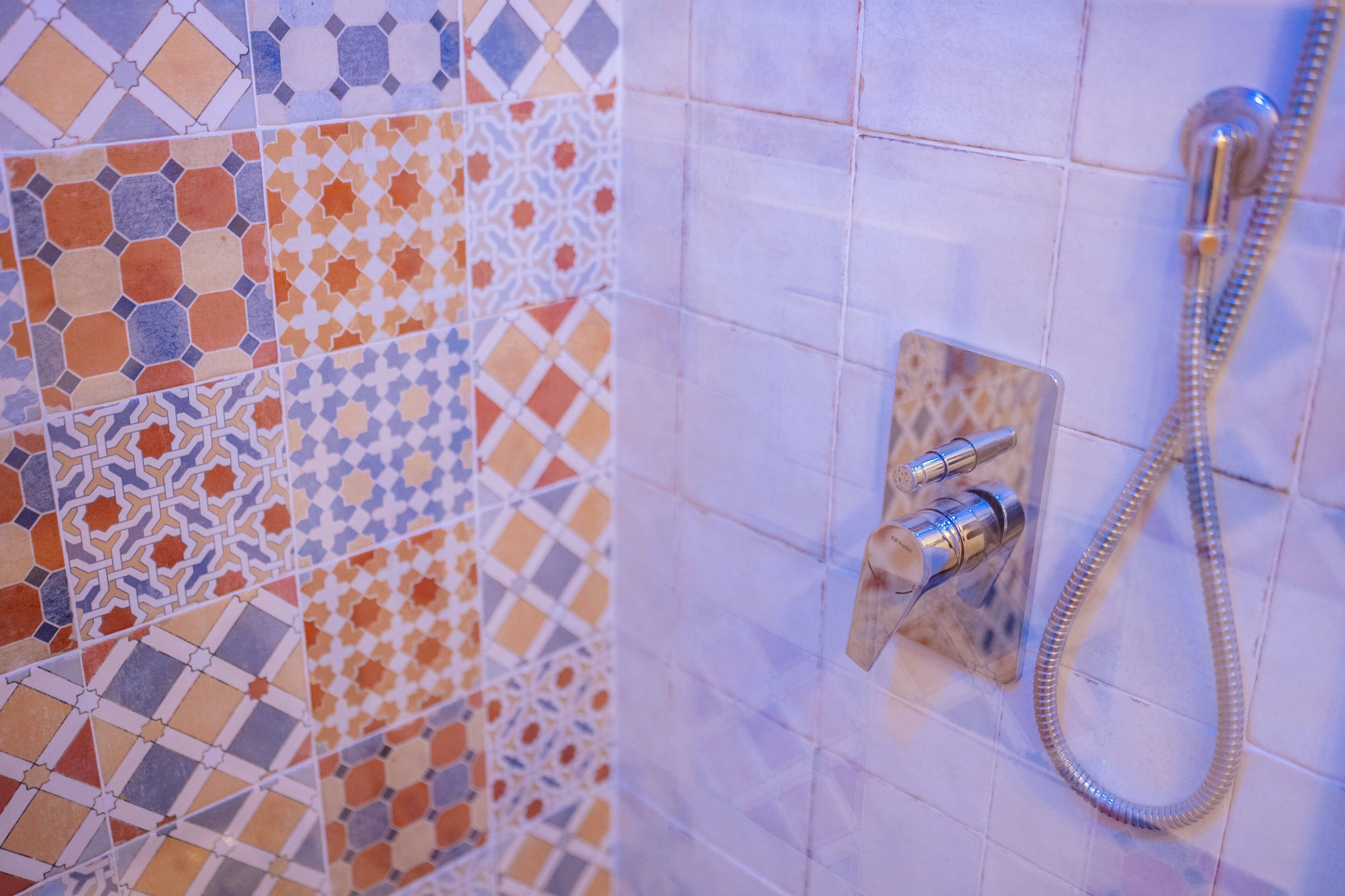 A bathroom with a shower and a tiled wall with a geometric pattern.