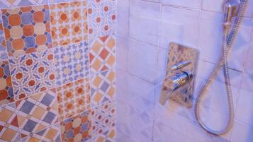 A bathroom with a shower and a tiled wall with a geometric pattern.