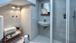 Une salle de bain moderne avec une douche à parois de verre, un lavabo blanc et un porte-serviettes où sont soigneusement pliées les serviettes.