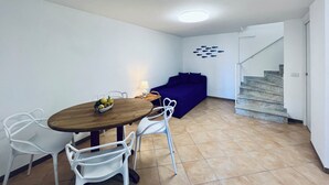 Un coin repas avec une table, des chaises et un saladier de fruits.