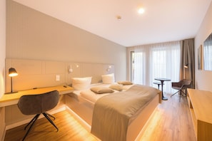 A hotel room with a bed, desk, chair, and a small table. - Design Apartments - Luise (Potsdam)