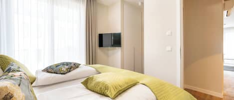 A hotel room with a bed, a television, and a door leading to another room.