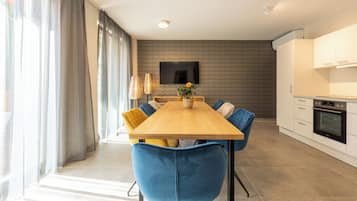 Un comedor moderno con una mesa de madera, sillas azules y un televisor de pantalla plana montado en la pared.