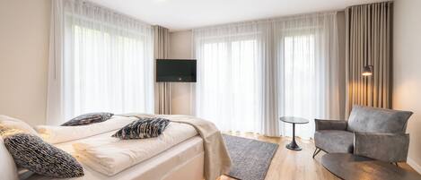 A hotel room with a bed, a sofa, a TV, and a small table.