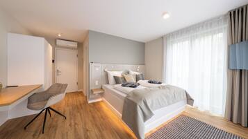 Ein modernes Schlafzimmer mit Bett, Nachttisch, Stuhl und Fernseher.