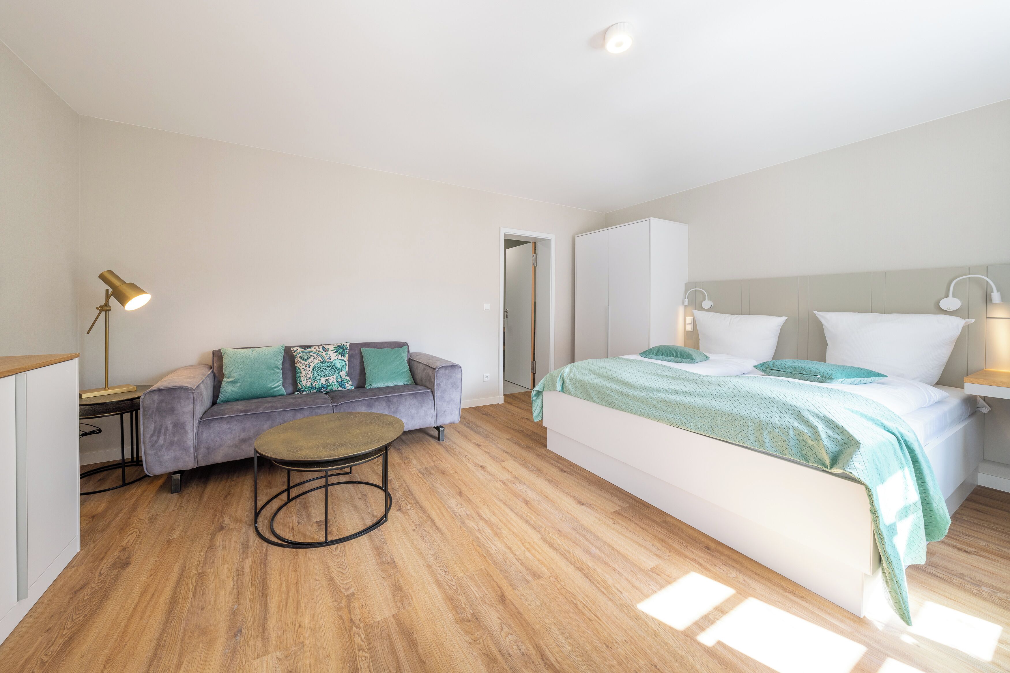 Une chambre à coucher avec un lit, un canapé, une petite table et une table de chevet.