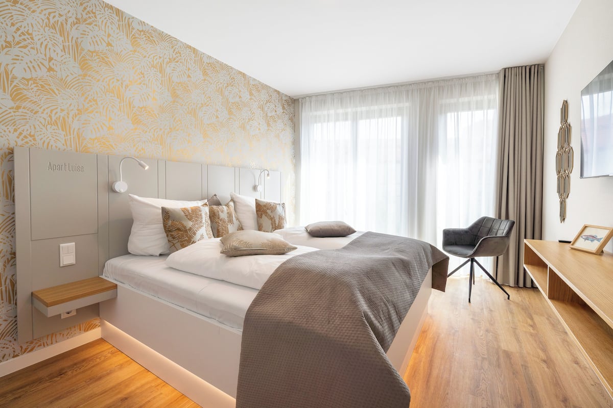 A modern hotel room with a large bed, a desk, and a chair.