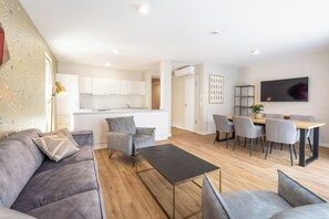 A modern living room with a sofa, coffee table, and dining area with chairs. - Design Apartments - Luise (Potsdam)