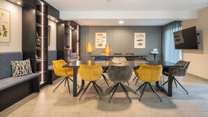 Un área de comedor moderna con una mesa larga, cuatro sillas y un sofá.