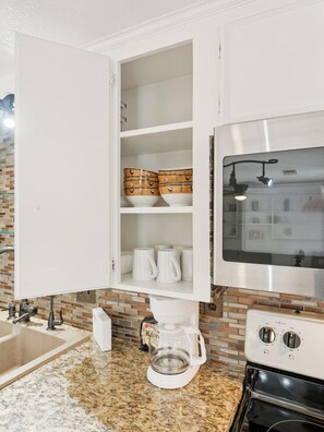 A kitchen with a coffee maker, a microwave, and a cabinet with dishes.