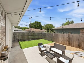 A patio with outdoor furniture, a wooden fence, and a lawn.