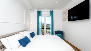 A modern hotel room with a large bed, a flat-screen TV, and a view of the outdoors. - YourHome - Il Nido Apartments  (Sant'Agnello)