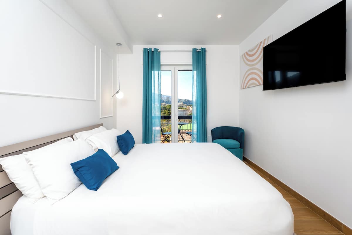 A modern hotel room with a large bed, a flat-screen TV, and a view of the outdoors.