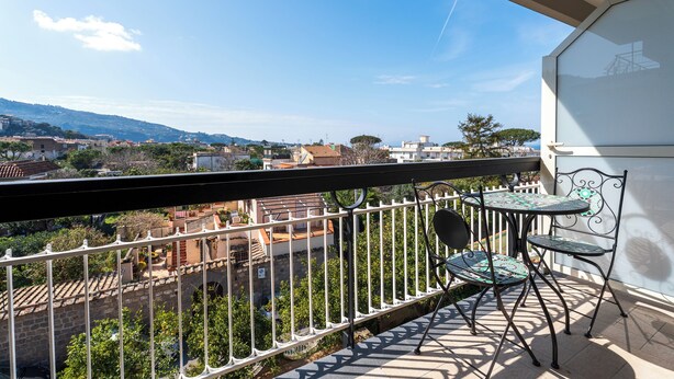 A balcony with a white railing, a small table, and two chairs. - YourHome - Il Nido Apartments  (Sant'Agnello)
