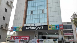 A multi-story building with signs for 'Hotel Krishna', 'Urbanpets', and 'Keshar Auto Parts'. - Hotel Krishna Inn (Ahmedabad)