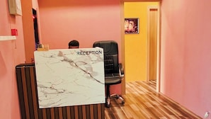 A reception area with a marble-patterned desk, a ceiling fan, and a wooden floor. - Hotel Krishna Inn (Ahmedabad)