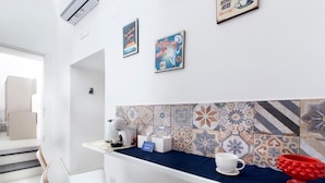 Eine moderne Küche mit blauer Arbeitsplatte, weißen Stühlen und einer gefliesten Spritzschutzwand.