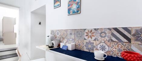 Una cocina moderna con encimera azul, sillas blancas y salpicadero de azulejos.