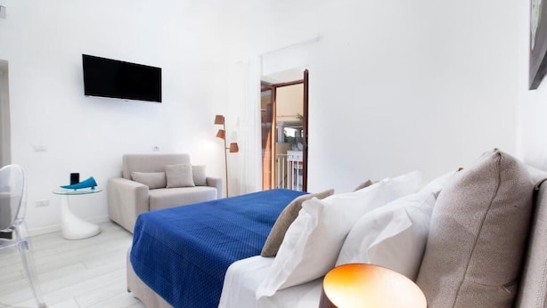 Ein modernes Hotelzimmer mit Bett, Fernseher, einem kleinen Tisch und einem Stuhl.