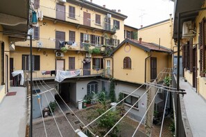 Ein Innenhof mit einer Hängebrücke, Gebäuden mit Balkonen und einem kleinen Garten.