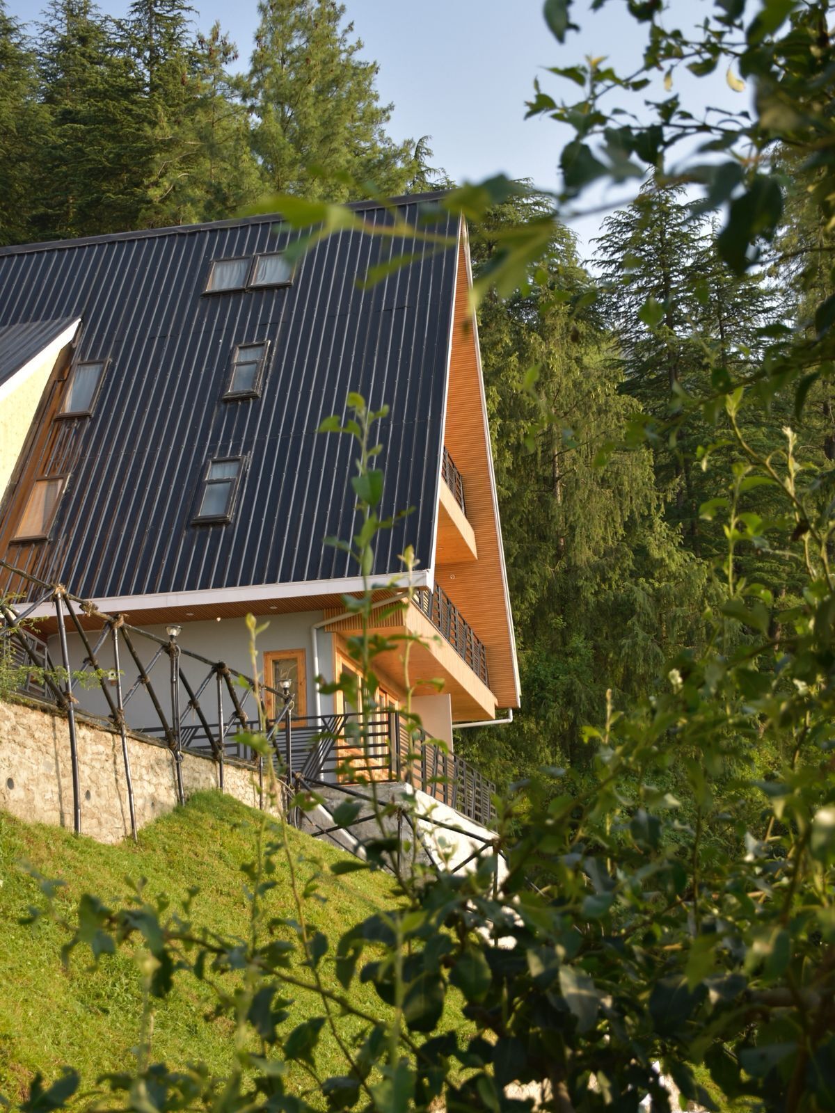 Une maison moderne dotée d’un toit en pente, de panneaux solaires et d’un balcon en bois.
