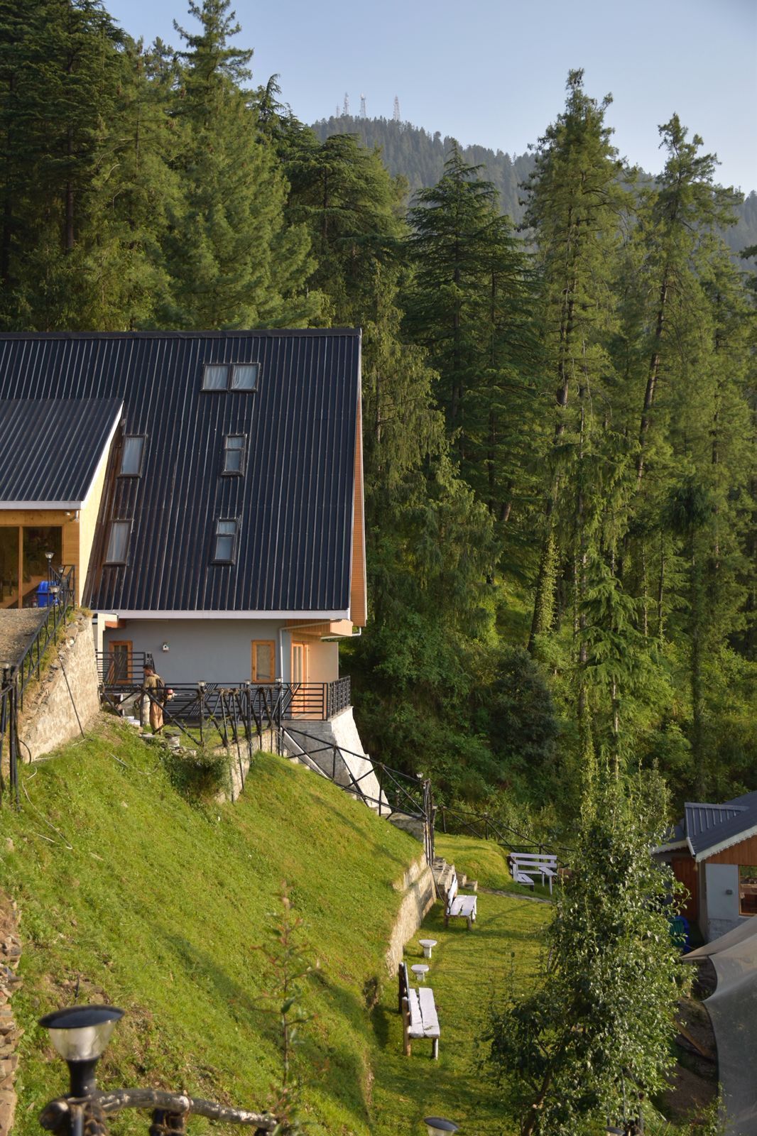 A modern house with a sloped roof, a stone staircase, and a small garden with outdoor seating.
