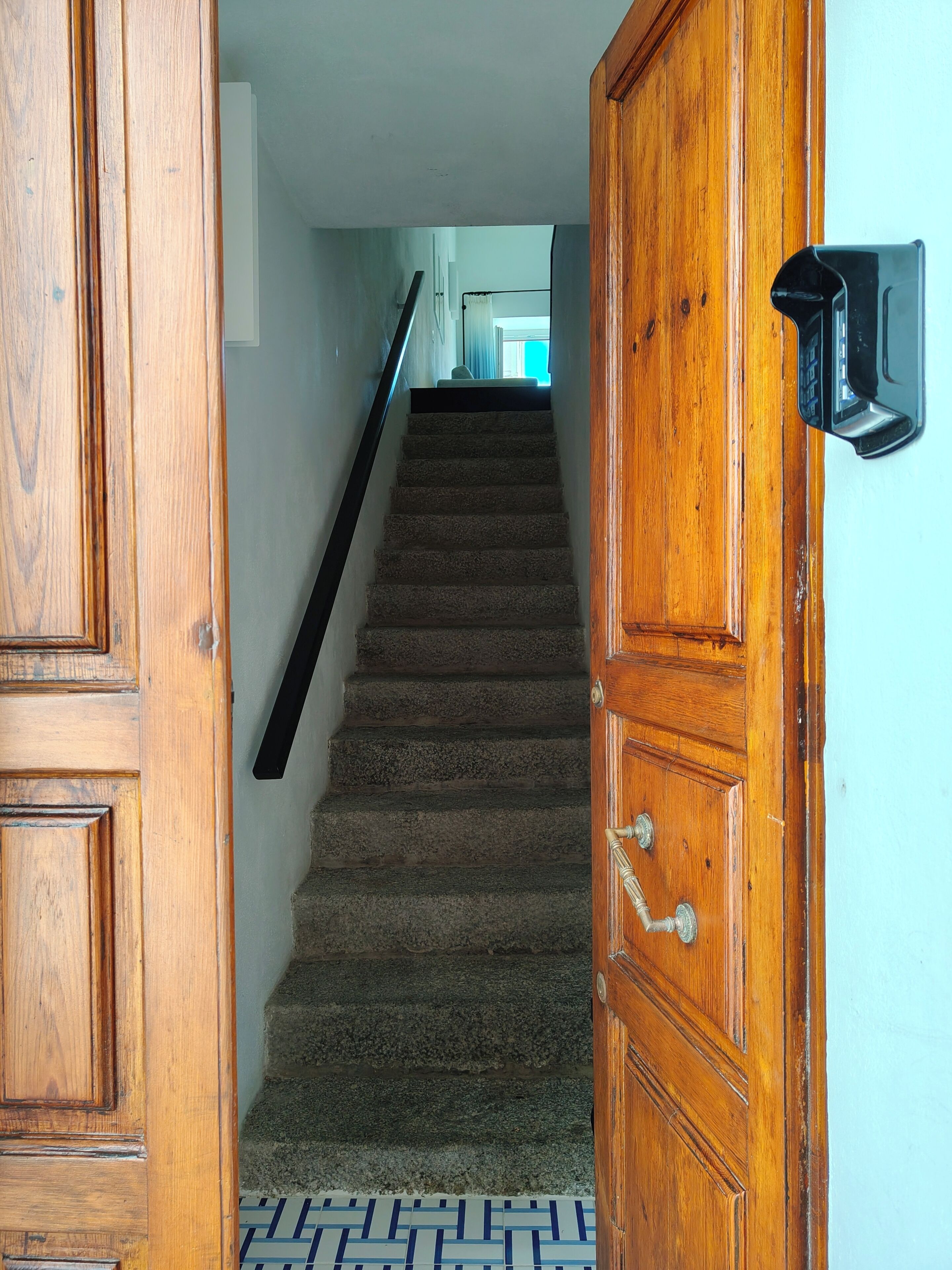 A wooden staircase leading to a room with a patterned floor.