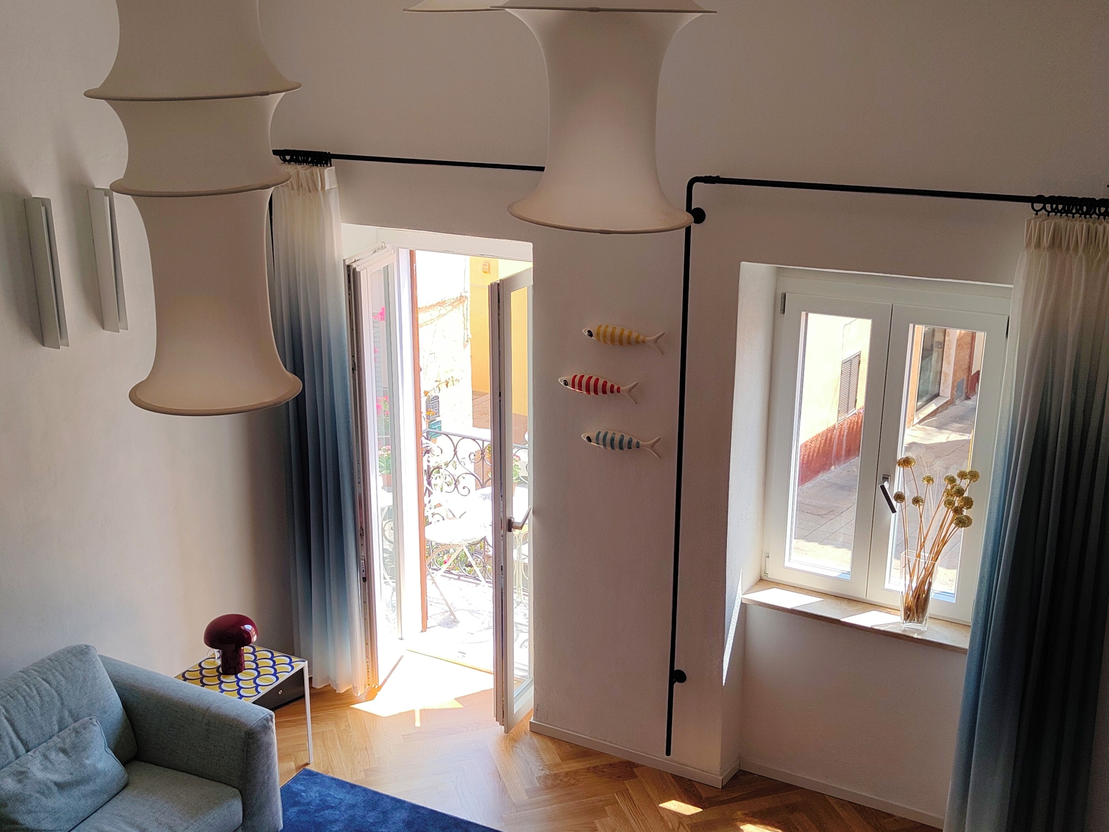 Une pièce comprenant un canapé, une table ornée d’un objet décoratif, une fenêtre avec des rideaux et une porte donnant sur l’extérieur.