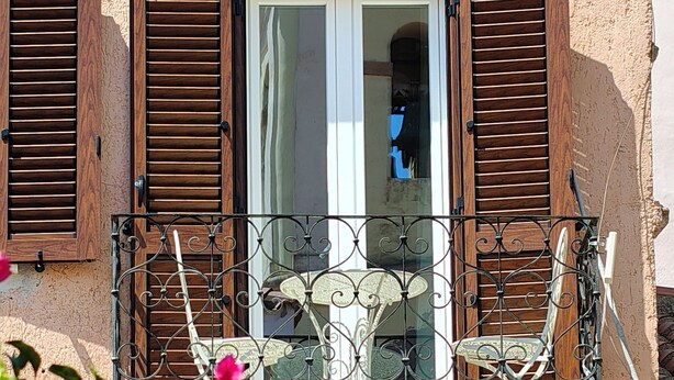 A balcony with a wrought iron railing, a small table, and a chair. - YourHome - La Maddalena Blue House (La Maddalena)