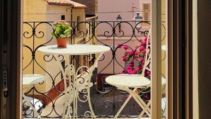 A balcony with a view of a tower, a pink building, and a white table with chairs. - YourHome - La Maddalena Blue House (La Maddalena)
