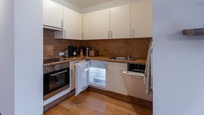 Una cocina compacta con armarios blancos, horno integrado y lavavajillas.