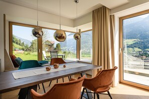 A dining area with a large table, chairs, and a view of a mountainous landscape. - Apartments VIU - 03 Great VIU (Bad Hofgastein)