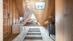 A wooden interior with a sloped ceiling, a small kitchenette, a sofa, a framed picture, and a staircase. - Javorina Residence (Zakopane)