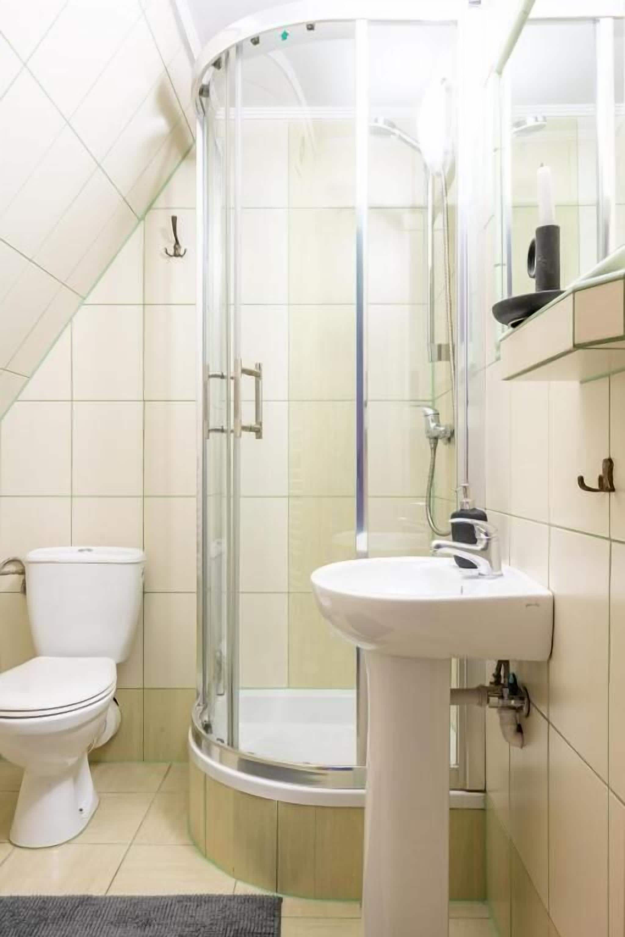 Une salle de bain avec une douche à parois de verre, un lavabo blanc et des toilettes.