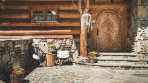 A rustic wooden cabin with a large wooden door, stone walls, and a stone staircase leading to the entrance. - Javorina Residence (Zakopane)