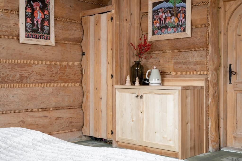 A wooden room with a bed, a cabinet, and two framed pictures on the wall.