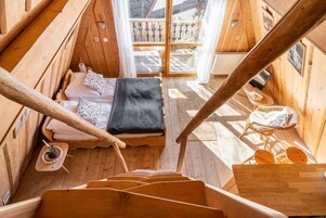 Una cabaña de madera con una cama, una pequeña mesa con una bebida y una silla.