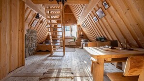 A wooden interior with a loft bed, a desk, and a stone wall. - Javorina Residence (Zakopane)