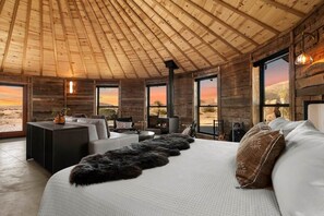 A room with a bed, a sofa, a coffee table, and a fireplace. - Mojave Yurt Featured in Rolling Stone, Stargaze (San Bernardino County)