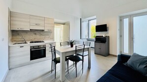 Een moderne keuken met een eetgedeelte, een aan de muur bevestigde televisie en een bank in de woonkamer.