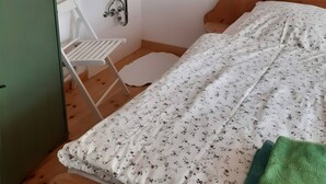 Quarto com uma cama, uma pia pequena e branca, um espelho e teto de madeira.